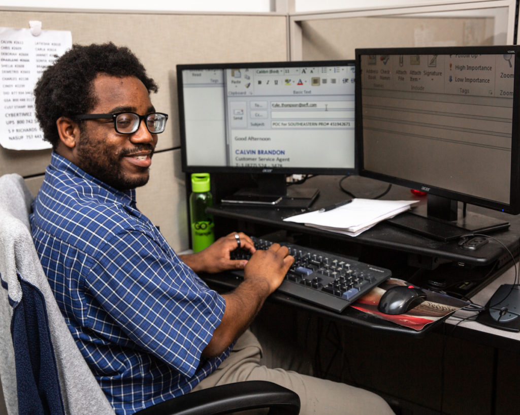 African American man with visual impairment sitting at computer with hands on keyboard