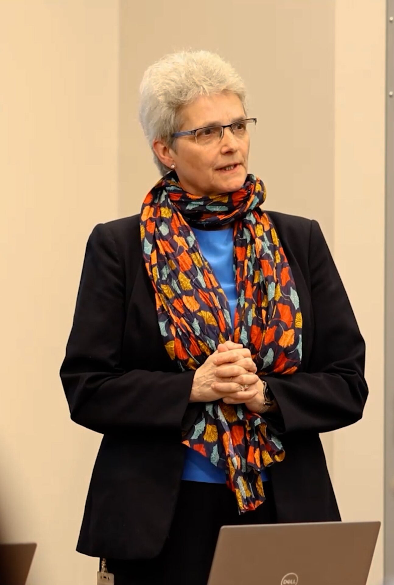 A woman stands in the front of a classroom and speaks.
